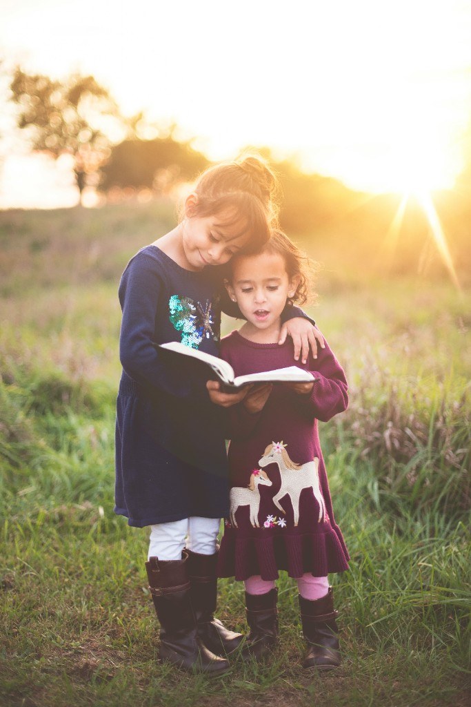 Two children reading together outdoors